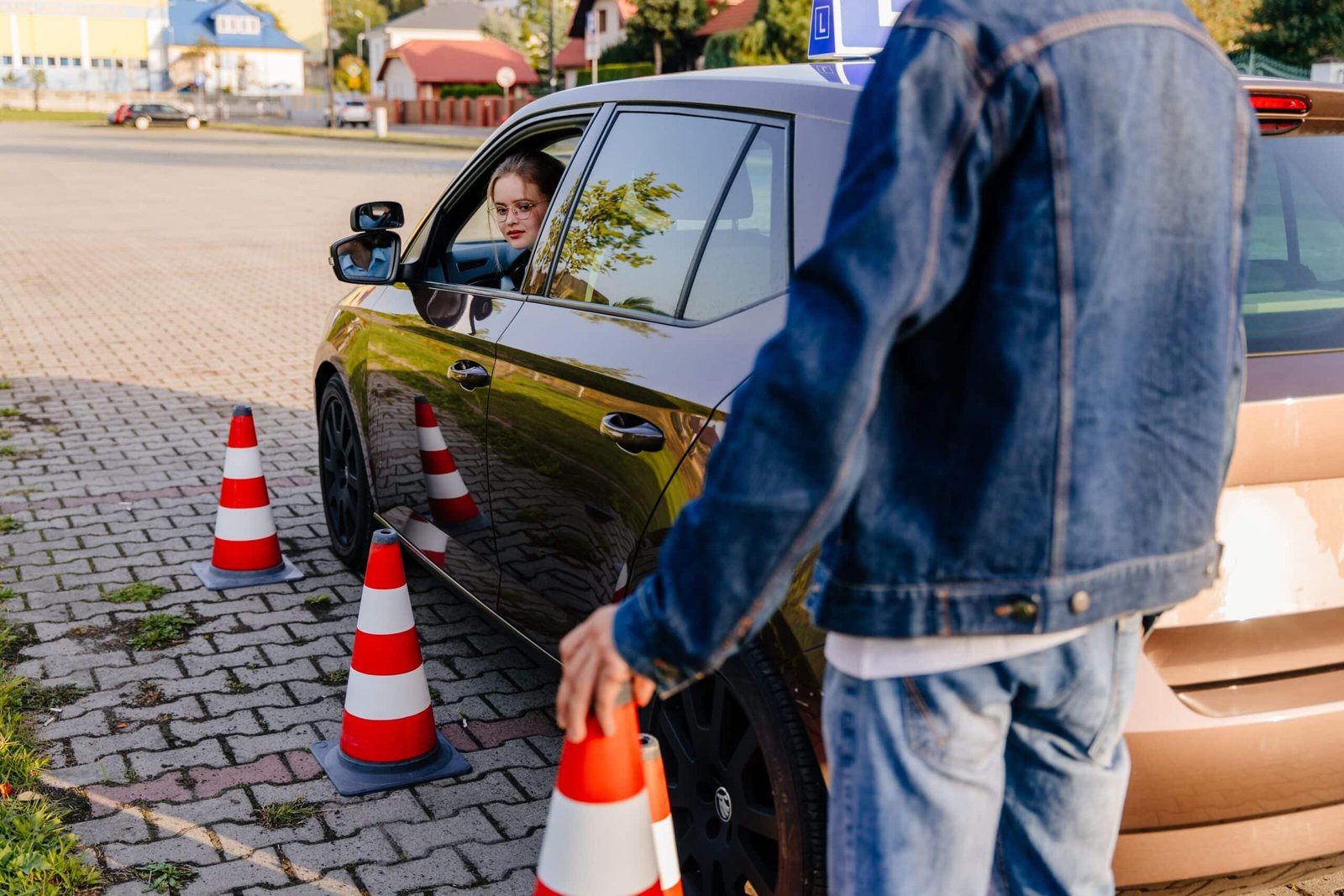Leerling in lesauto oefent parkeervaardigheden tussen pionnen onder begeleiding van instructeur