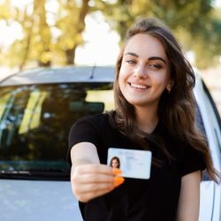 Zelfverzekerde jonge vrouw achter het stuur tijdens rijles